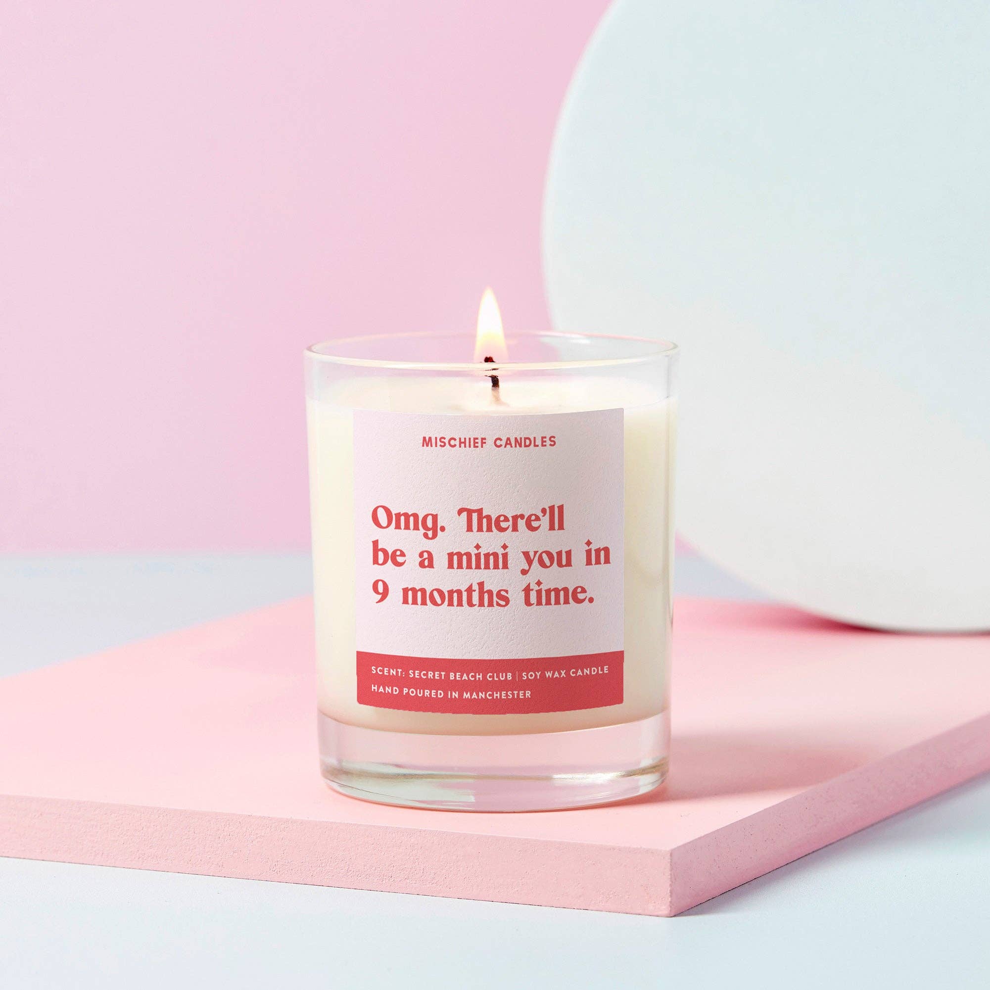 A pale pink candle with the text 'Omg. There'll be a mini you in 9 months time.