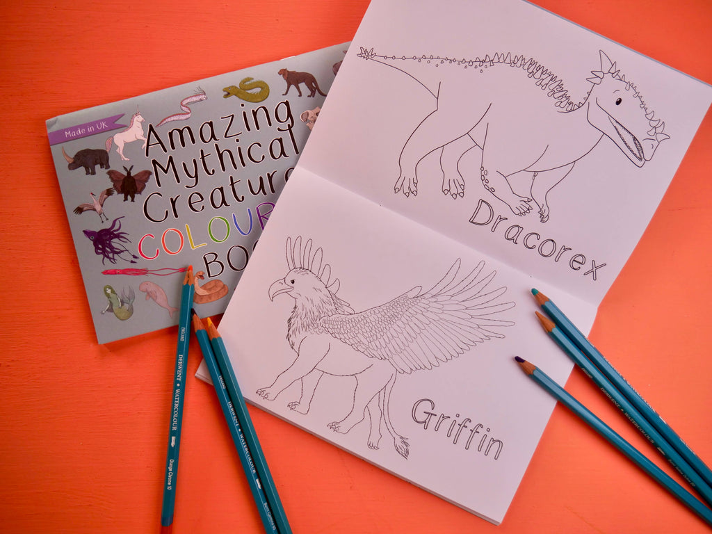 Coloring book with mythical creature illustrations and coloring pencils on an orange background