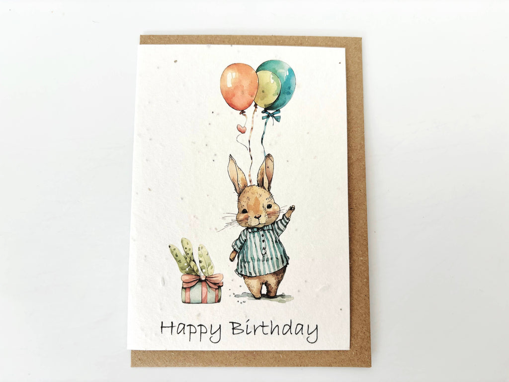 Birthday card with a rabbit holding balloons and a gift, on a white background