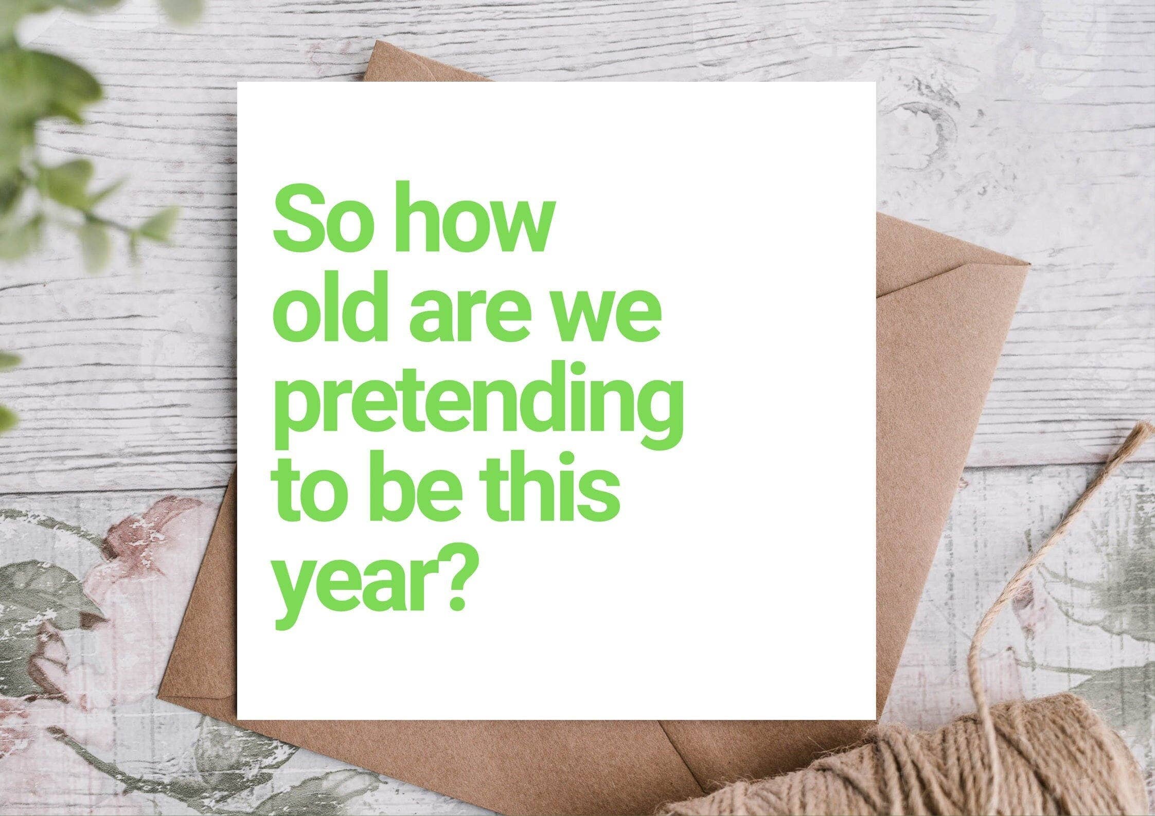 Card with text 'So how old are we pretending to be this year?' on white card with green text, kraft envelope.
